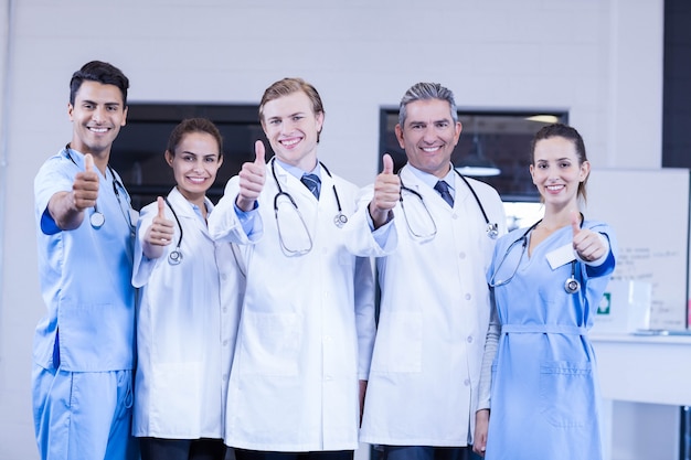 Retrato del equipo médico que pone los pulgares para arriba y que sonríe en hospital