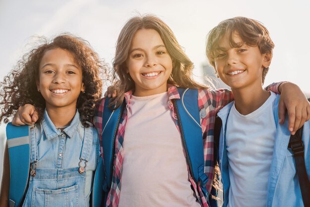 Foto retrato de escolares que se abrazan y sonríen en cámara al aire libre