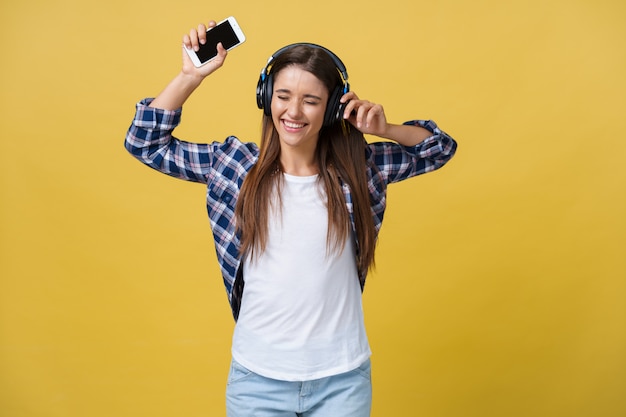 Retrato de escuchar alegre hermosa mujer caucásica a la música en el teléfono móvil.