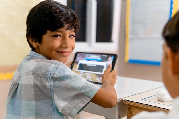 Retrato de una escuela primaria hispana. Niños usando tabletas en clase.