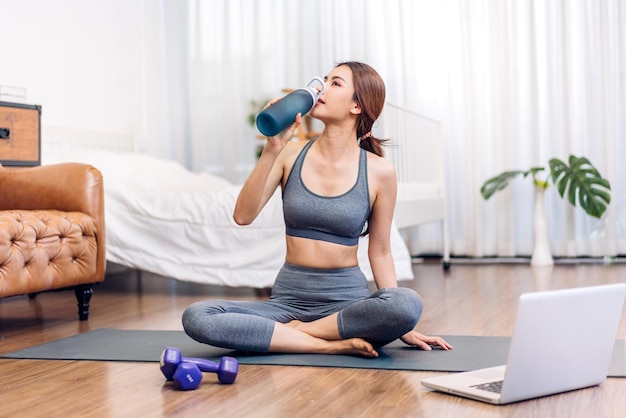 Retrato esporte beleza corpo magro mulher bebendo água de uma garrafa enquanto relaxa e se sente fresco em casa Conceito de estilo de vida saudável