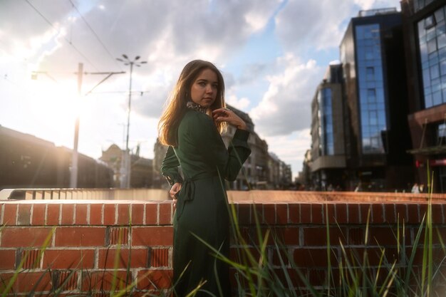 Foto retrato de estilo callejero de moda de una hermosa joven de cabello castaño antes del atardecer.