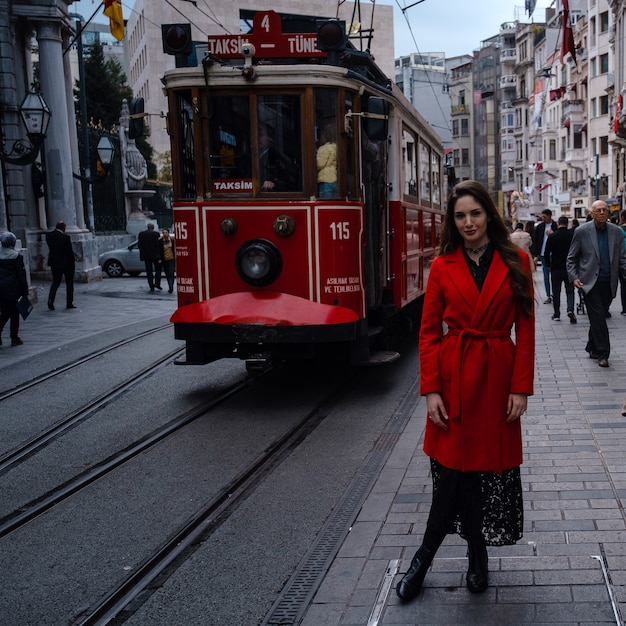 Retrato de estilo de moda de joven y bella mujer posando en las calles de la ciudad de Taksim con tren rojo