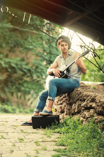 Retrato de estilo retro de un joven guitarrista tocando bajo el puente