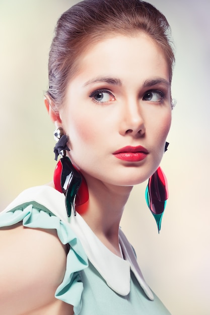 Retrato de estilo retro de mujer joven vistiendo elegantes aretes de plástico