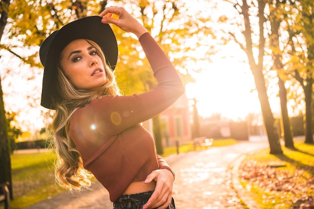 Retrato de estilo de vida de una chica caucásica con sombrero en un bosque caminando en otoño