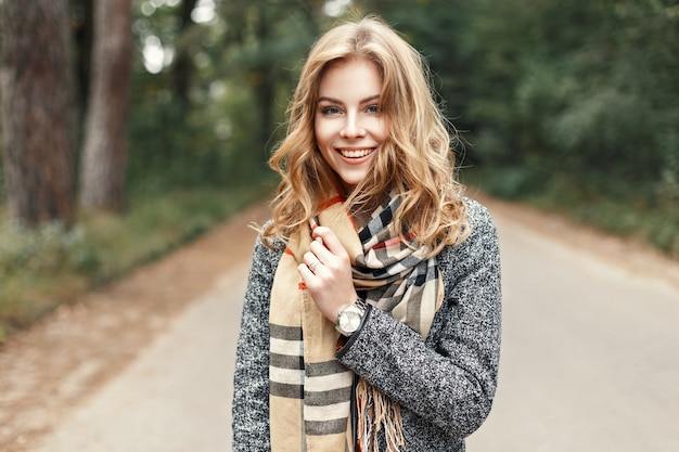 Retrato de estilo de vida feliz de una hermosa joven modelo con una dulce sonrisa en una cálida bufanda de otoño.