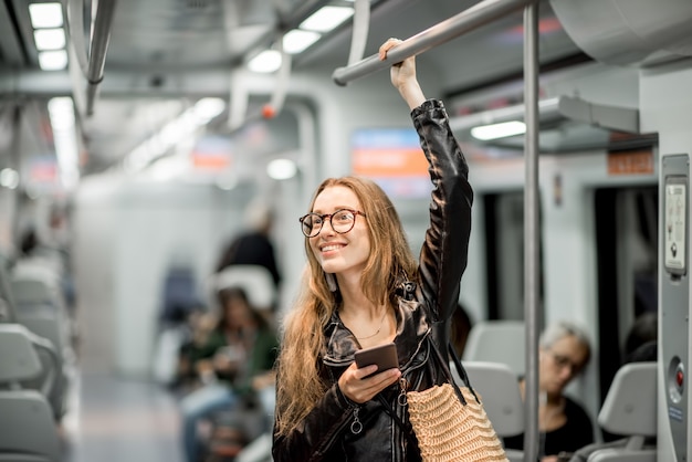 Retrato de estilo de vida de una joven empresaria de pie con un teléfono inteligente en el tren moderno