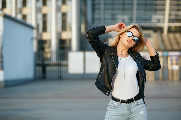 Retrato de estilo de vida de una joven increíble con gafas de espejo y chaqueta casual. Espacio para texto