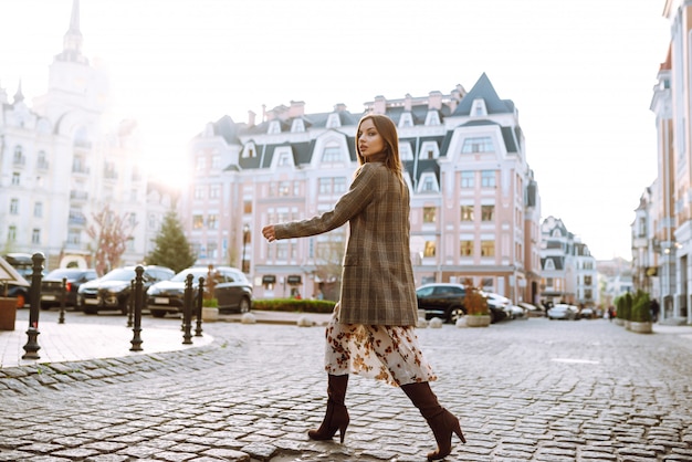 Retrato de estilo de vida de moda de mujer bonita feliz joven caminando en la calle al atardecer. Chica con estilo y elegante.