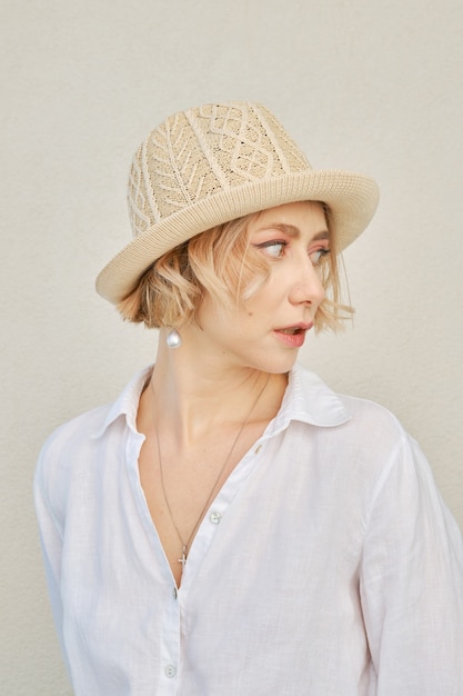 Retrato de estilo de vida de una mujer con camisa blanca y sombrero de paja dando marcha atrás