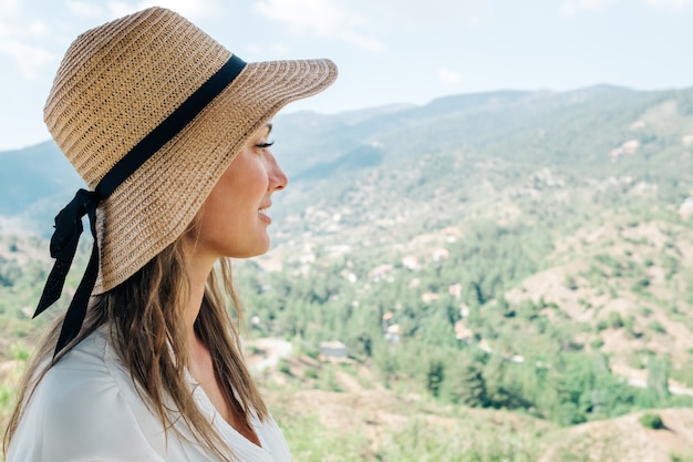 Retrato de estilo de vida soleado de mujer joven inconformista, con sombrero de paja. Retrato con paisaje de valle