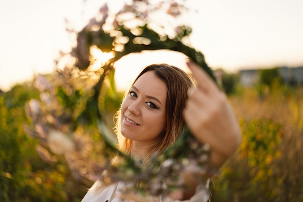 Foto retrato de estilo de vida de verano de hermosa mujer joven en una corona de flores silvestres en la cabeza