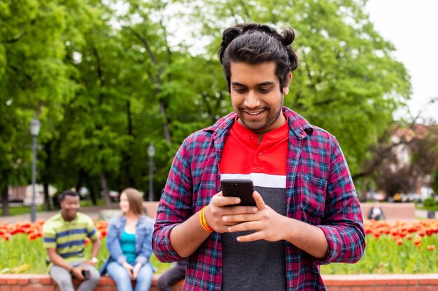 Retrato de un estudiante afroamericano que envía mensajes a un amigo en un teléfono inteligente