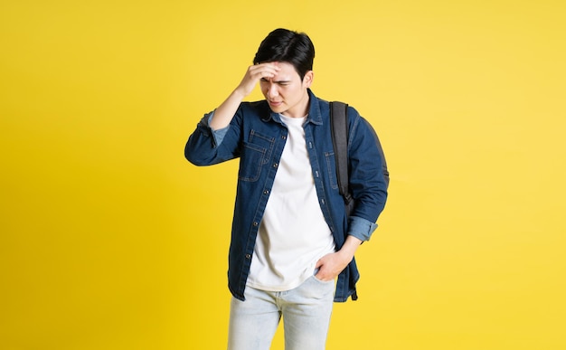 Foto retrato de un estudiante asiático posando sobre un fondo amarillo