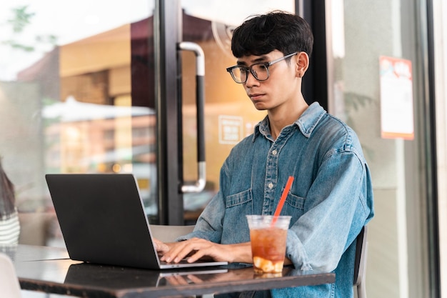 Retrato de un estudiante asiático sentado en una cafetería