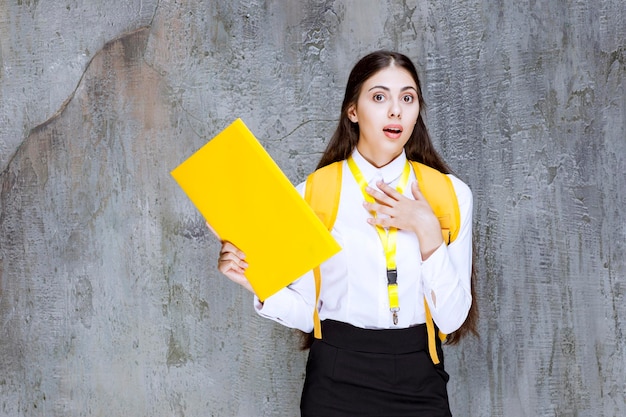 Retrato de estudiante bonita con cuaderno amarillo posando para la cámara. foto de alta calidad