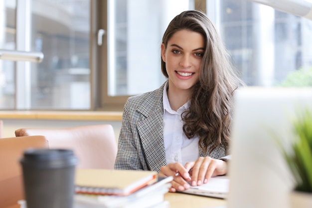 Retrato de una estudiante bonita con ordenador portátil en la biblioteca.