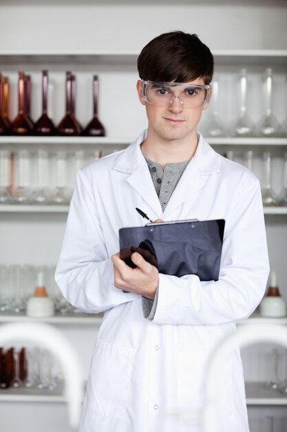 Retrato de un estudiante de ciencia masculina escribiendo en un portapapeles