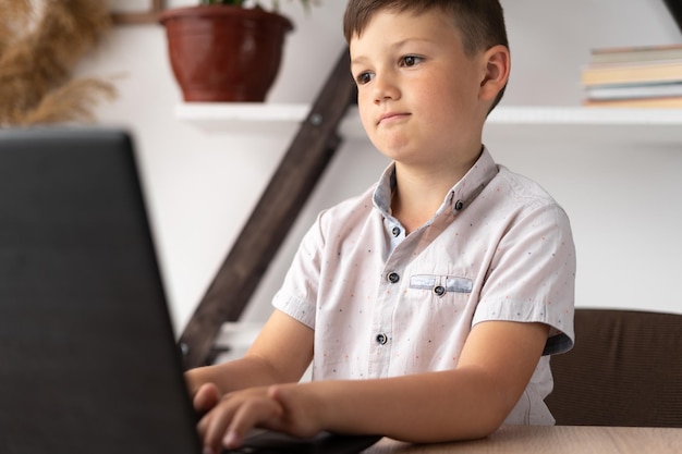 Retrato de un estudiante concentrado escribiendo en el teclado de una computadora portátil en casa o jugando un juego de computadora virtual estudiante motivado que estudia de forma remota el niño prodigio escribe un programa para PC