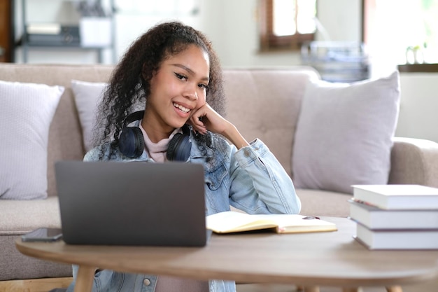 Retrato de una estudiante feliz de piel oscura sonriendo a la cámara una alegre chica hipster afroamericana disfrutando del aprendizaje y la preparación para el trabajo del curso