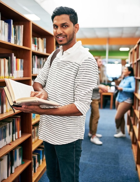 Retrato de un estudiante y un hombre indio leyendo un libro en la biblioteca para la educación, el aprendizaje y el estudio en la universidad.