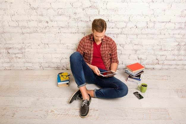 Retrato de estudiante con libros y tableta preparándose para exámenes