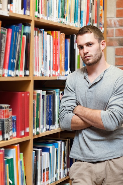 Retrato de un estudiante masculino apoyado en un estante