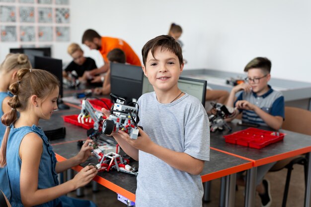 Retrato de un estudiante masculino que construye un vehículo robot en la clase de codificación de computadoras después de la escuela