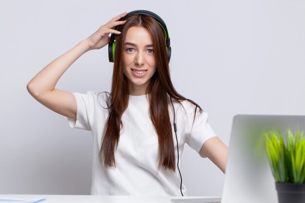 Retrato de un estudiante o una mujer de negocios joven con auriculares y portátil
