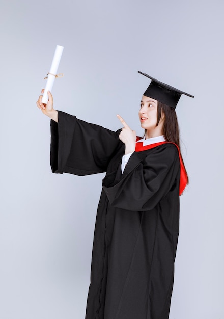 Retrato de estudiante de posgrado en bata mostrando certificado universitario. Foto de alta calidad