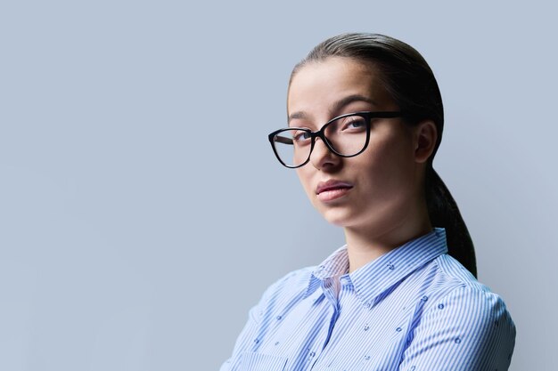 Foto retrato de una estudiante de secundaria copyspace fondo gris cerca de una mujer segura y seria con gafas mirando a la cámara