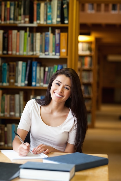 Retrato de un estudiante sonriente escribiendo un papel