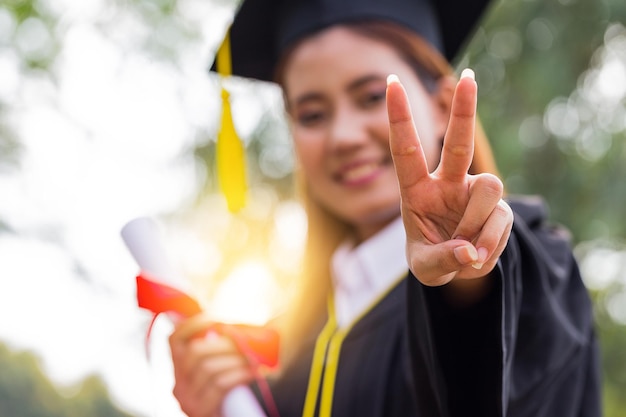 Foto retrato de un estudiante sonriente gestando un signo de paz en un parque