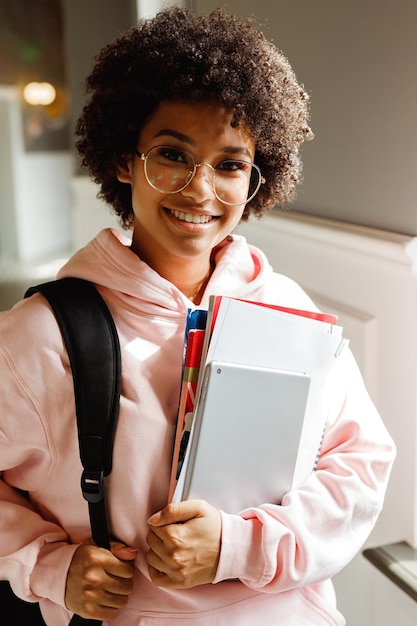 Retrato de un estudiante universitario adolescente sonriente sosteniendo libros