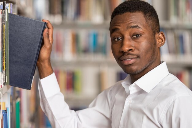 retrato, de, un, estudiante universitario, hombre, en, biblioteca, poca profundidad de campo