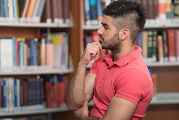 retrato, de, un, estudiante universitario, hombre, en, biblioteca, poca profundidad de campo