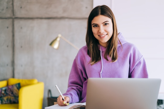 Retrato de estudiante universitario joven que estudia con la computadora portátil, preparándose a distancia para el examen de prueba, escribiendo un ensayo haciendo los deberes en casa, concepto de educación a distancia.