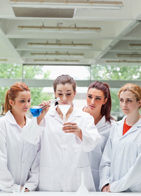 Retrato de estudiantes de ciencia vertiendo líquido en un matraz