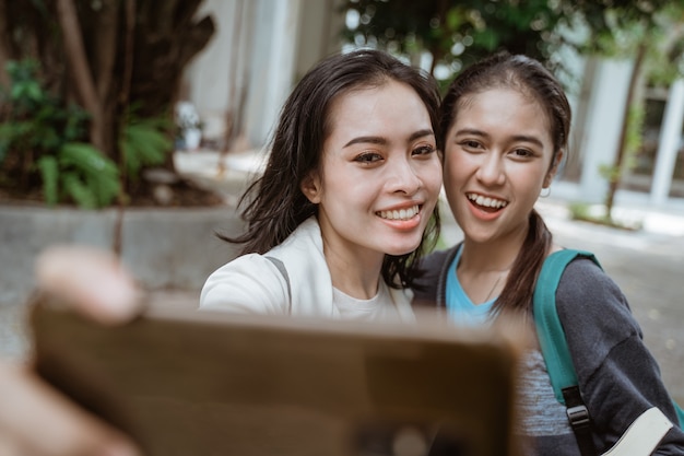 Retrato de estudiantes muy felices y sonrientes toman un selfie en el patio del campus