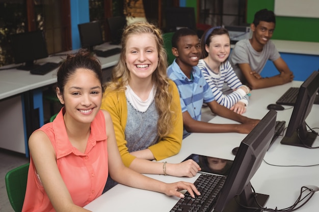 Retrato de estudiantes sonrientes que estudian en el aula de informática