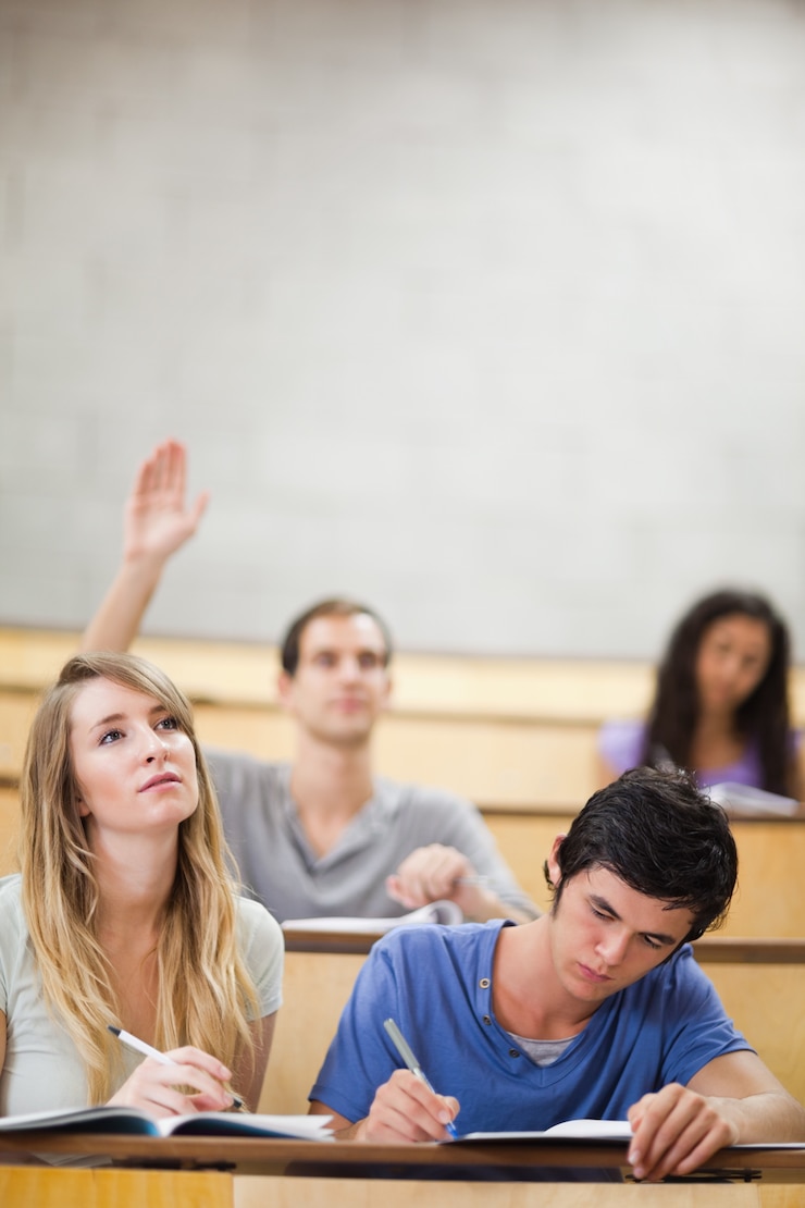 Foto retrato de estudiantes tomando notas mientras su compañero levanta su mano