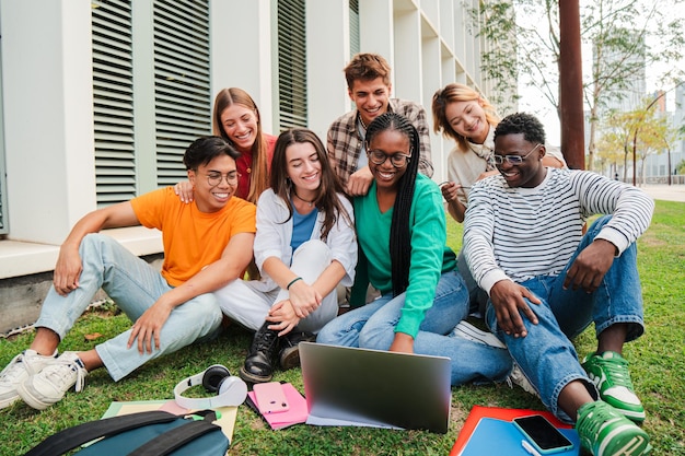 Retrato de estudiantes universitarios multirraciales usando una computadora portátil mientras se divierten viendo divertidos