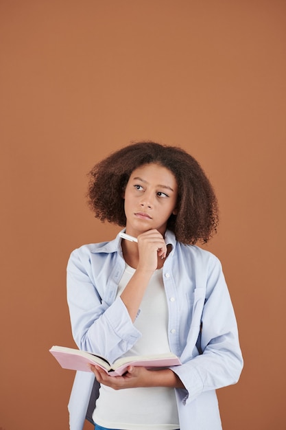 Retrato de estudio de una adolescente pensativa tomando notas en su diario o planificador