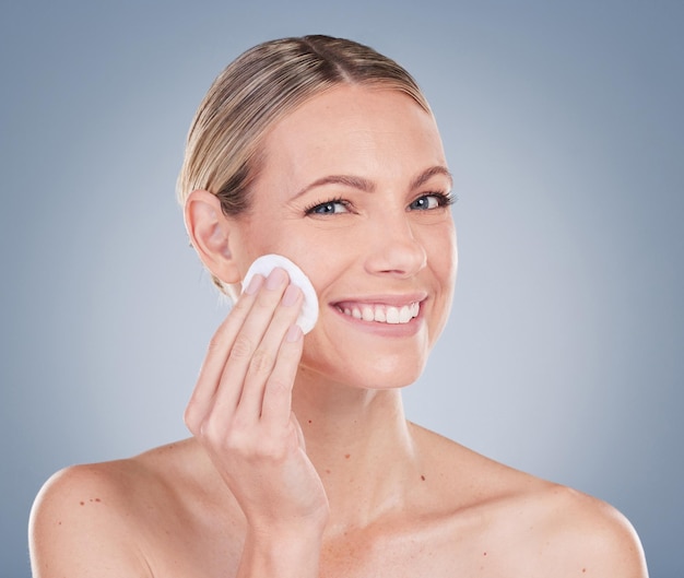 Retrato de estudio de una atractiva joven exfoliando su rostro contra un fondo gris