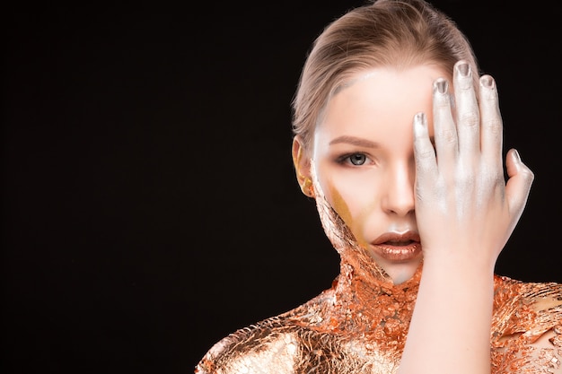Foto retrato de estudio de belleza de glamour modelo rubia con lámina dorada brillante sobre sus hombros. espacio para texto