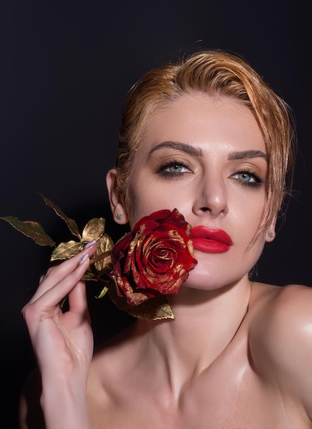 Retrato de estudio de belleza hermosa modelo con flor rosa roja aislada en char de fondo de estudio negro