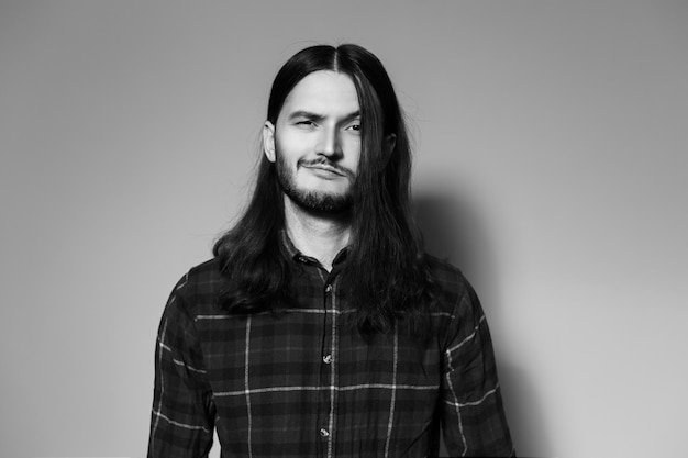 Retrato de estudio en blanco y negro de un joven sonriente con el pelo largo