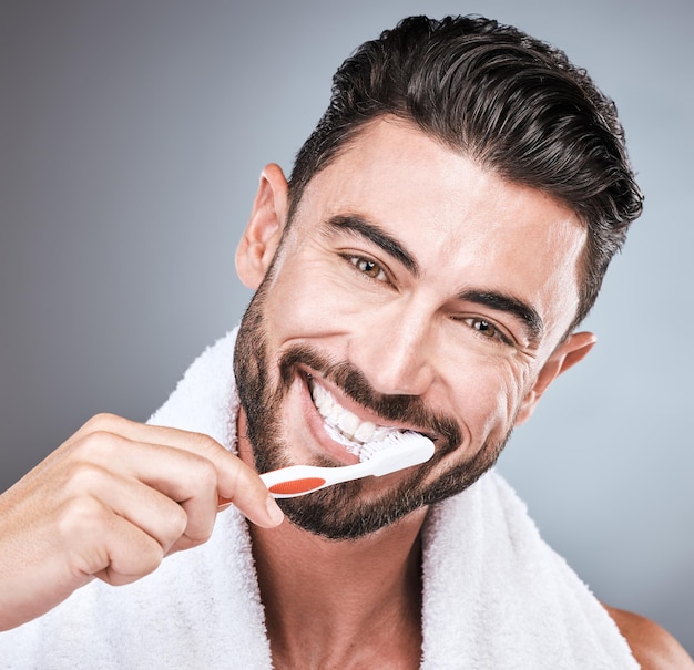 Retrato de estudio de cepillado de dientes y hombre con cepillo de dientes bienestar dental y cuidado bucal saludable Modelo masculino de cara feliz y limpieza oral para una sonrisa de aliento fresco y felicidad facial con pasta de dientes