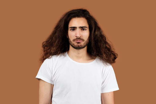 Retrato de estudio de un chico árabe triste con el pelo largo y rizado